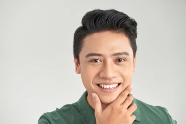 Gri duvar arkasında yalnız duran yakışıklı, neşeli, olgun bir adam resmi.