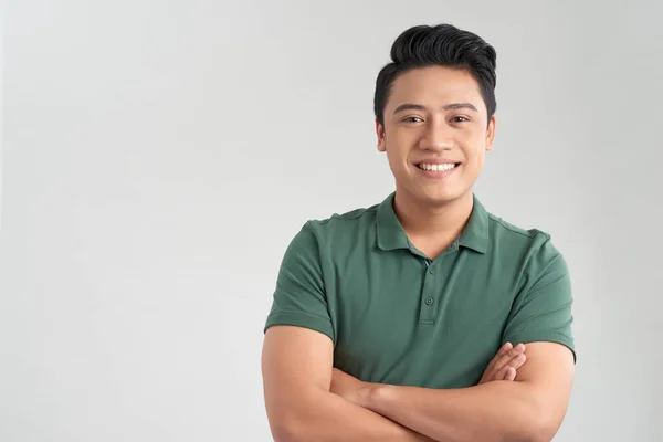 Çekici bir adam gülümsüyor ve kollarını kavuşturup beyaz bir arkaplanda tek başına dikilirken;