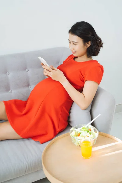 Junge Schwangere Telefonieren Auf Dem Sofa Essen Salat Trinken Orangensaft — Stockfoto