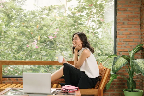 Morning scene of young woman right hand writing on notebook beside window in cafe. Freelance working lifestyle