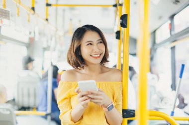 Gülümseyen güzel kadın otobüste dururken telefonu kullanıyor..