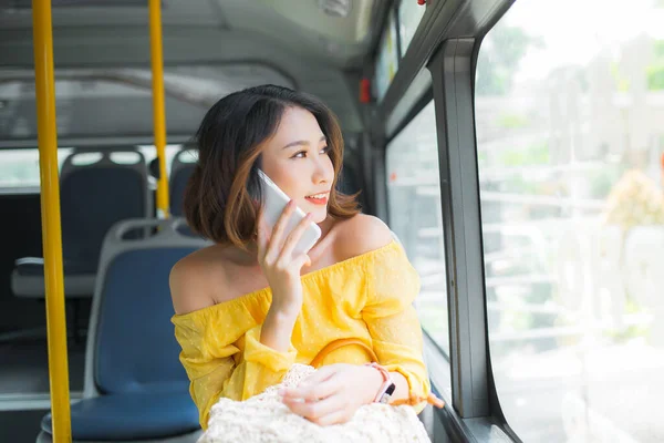 Young Asian woman using smartphone when sitting on bus