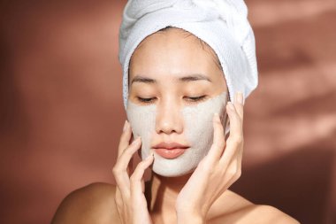 Yüzüne kilden maske takan genç bir kadın.