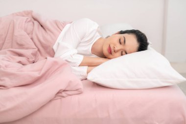 Genç ve güzel bir kadın yatağında uyuyor ve sabahları dinleniyor.