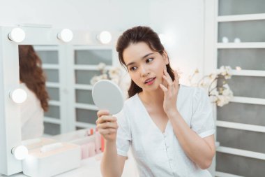 İnsanlar ve güzellik anlayışı. Yatak odasında yüzü aynalı güzel bir kadın tenine dokunuyor.