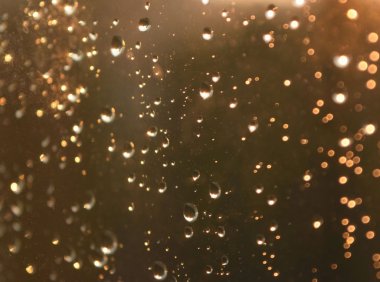 Gün batımında cam üzerine yağmur damlaları.