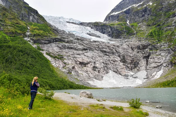 The young girl looks at the Boyabreen glacier. Melting glacier f — Stock Photo, Image