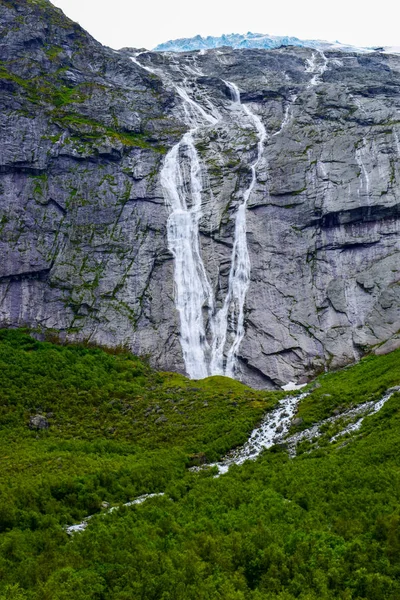Waterfall and river which is located near path to the Briksdalsbreen (Briksdal) glacier. The melting of this glacier forms waterfall and river with clear water. Jostedalsbreen National Park. Norway.