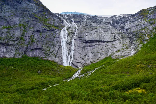 Waterfall and river which is located near path to the Briksdalsbreen (Briksdal) glacier. The melting of this glacier forms waterfall and river with clear water. Jostedalsbreen National Park. Norway.