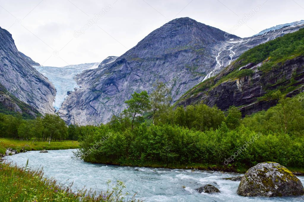 Waterfall and river which is located near path to the Briksdalsbreen (Briksdal) glacier. The melting of this glacier forms waterfall and river with clear water. Jostedalsbreen National Park. Norway.