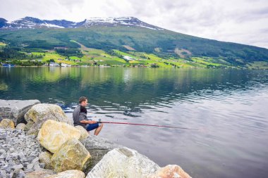 Adam Innvikfjord 'da balık tutuyor. Innvikfjord, Sogn og Fjordane 'nin Stryn belediyesinde Nordfjord' un bir alt fiyordudur. Norveç.