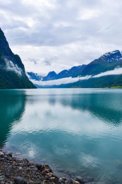 Jostedalsbreen Ulusal Parkı 'nın buzullarının bulunduğu güzel Oldevatnet buzul gölü ve sisli dağların manzarası. Norveç.