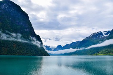 Jostedalsbreen Ulusal Parkı 'nın buzullarının bulunduğu güzel Oldevatnet buzul gölü ve sisli dağların manzarası. Norveç.