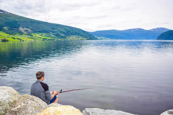 Adam Innvikfjord 'da balık tutuyor. Innvikfjord, Sogn og Fjordane 'nin Stryn belediyesinde Nordfjord' un bir alt fiyordudur. Norveç.