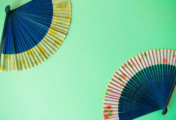 Composition of navy blue female hand fans close-up on the light blue paper background. Subject photo for design with copy space in minimal style, template for lettering or text.