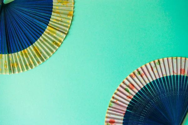 Composition of navy blue female hand fans close-up on the light blue paper background. Subject photo for design with copy space in minimal style, template for lettering or text.