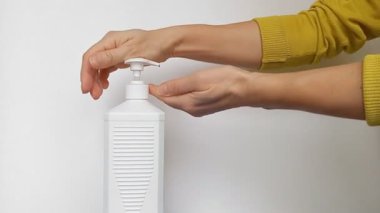 Kadın virüslerden ve bakterilerden korunmak için ellerini antiseptikle dikkatlice dezenfekte ediyor. Dezenfekte spreyi, yüzeydeki bakteri ve virüslerin% 99.9 'unu güvenli bir şekilde öldürüyor. Beyaz arkaplan.