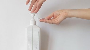 Kadınların elleri akıllı telefonun yüzeyini virüslere ve bakterilere karşı özel bir aletle dezenfekte eder. Dezenfekte spreyi, yüzeydeki bakteri ve virüslerin% 99.9 'unu güvenli bir şekilde öldürüyor..