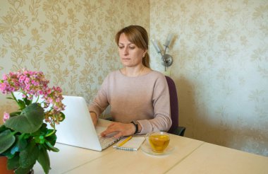 Genç kadın evden çıkmadan bilgisayarın başında uzaktan çalışıyor. Karantina döneminde evden uzak çalışma ve kendini izole etme.