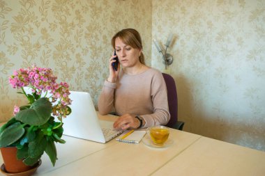 Genç kadın evden çıkmadan bilgisayarın başında uzaktan çalışıyor. Karantina döneminde evden uzak çalışma ve kendini izole etme.