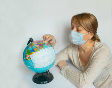 Korunaklı maskeler içindeki kadın ve Dünya küresi, tüm gezegendeki insanların Coronavirus salgını ve salgını nedeniyle karantinaya alındığının bir simgesidir. Boşluğu, afişi ya da şablonu kopyala.