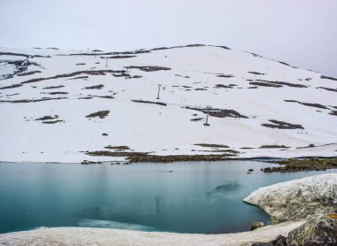 Stryn Sommerski kayak merkezinin yakınındaki asansör tüm yıl boyunca buzul kayağı yapmasıyla ünlüdür. Karlı yaz manzarası ve erimiş suyla dolu göl. Stryn, Vestland ilçesi. Norveç. Küresel ısınma ve iklim değişikliği.