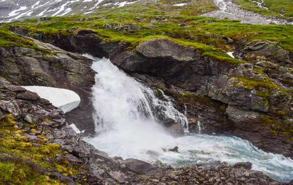 Waterfall and river with clear water, formed by melting glacier and snow high in the mountains. Jostedalsbreen National Park. Norway
