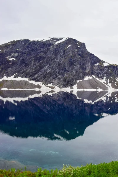 Eriyen kar ve buzulun sonucu oluşan saf erimiş suyla dolu göl. Küresel ısınma, iklim değişikliği. Sakin sulardaki kayaların güzel yansıması.