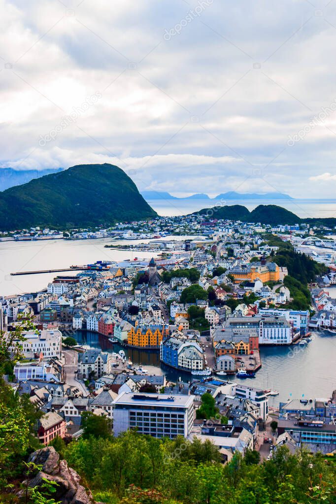 The amazing sunset over Alesund cityscape. Neoclassical and neo-Gothic stone buildings. Art Nouveau architecture. Sun rays illuminate Atlantic Ocean and islands. View from Aksla viewpoint. Norway.
