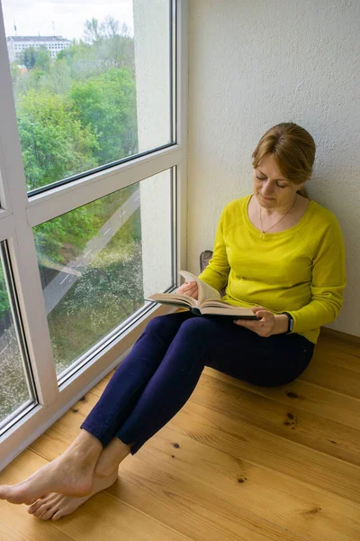 Beyaz Bir Kadın Karantina Döneminde Panoramik Pencerenin Yanında Oturmuş Kitap — Stok fotoğraf