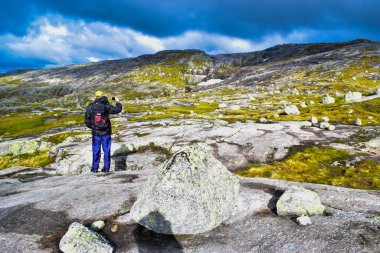 Turist Kjeragbolten yolunda. Norveç 'in Kjerag Dağı' ndaki Lysefjorden 'dan 984 metre yükseklikte kalan ünlü kaya parçasının bulunduğu inanılmaz Norveç manzaraları..