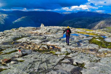 Turist Kjeragbolten yolunda. Norveç 'in Kjerag Dağı' ndaki Lysefjorden 'dan 984 metre yükseklikte kalan ünlü kaya parçasının bulunduğu inanılmaz Norveç manzaraları..