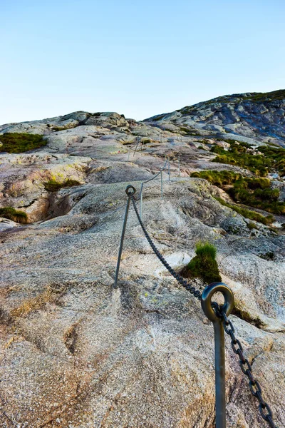 Chains on pathway to famous Kjeragbolten to help go up on climb steep cliffs. Kjeragbolten is a rock stuck between two mountains above Lysefjorden on mountain Kjerag in Forsand municipality, Norway.