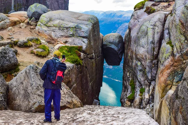 游客给世界上最危险的石头拍了一张照片 Kjeragbolten是位于挪威Kjerag山上Lysefjorden上空984米的岩石 — 图库照片