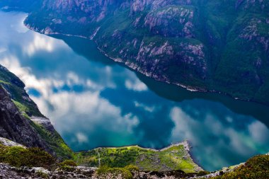 Lysefjorden 'ın muhteşem dağ manzarası mavi suya yansıyan bulutlarla. Kjerag Platosu 'ndan görüntü, 984 metre yükseklikte Kjeragbolten' in iki kayasının arasına sıkışmış. Norveç.