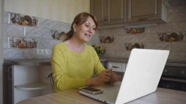 Bilgisayarlı beyaz bir kadın evde mutfaktayken online sohbet ve sosyal ağlarda iletişim kuruyor. Blog yazarı takipçileri için canlı yayın yapıyor. Ev eğlencesi..