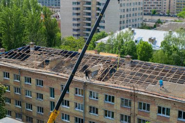 İşçiler eski bir kırmızı tuğla binanın çatısını onarıp yenilediler. Bahar inşaatı. Şehir binalarının düzgün bir şekilde onarımı ve bakımı. Şehir mimarisi. Genel plan.