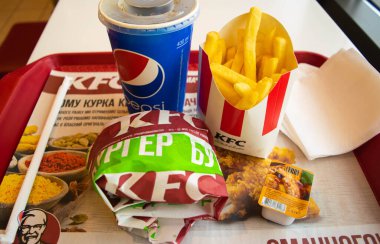 Kiev, Ukrayna - 8 Mart 2020: Popüler bir fast food restoranı olan KFC 'de yiyecek ve içecek. Kentucky Fried Chicken olarak bilinen popüler fast food zinciri. Patates kızartması, Pepsi ve köri soslu burger..
