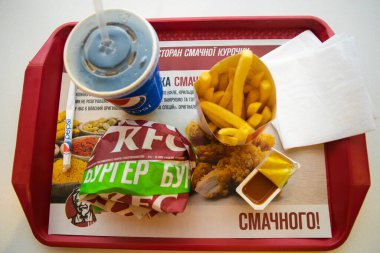 Kiev, Ukrayna - 8 Mart 2020: Popüler bir fast food restoranı olan KFC 'de yiyecek ve içecek. Kentucky Fried Chicken olarak bilinen popüler fast food zinciri. Patates kızartması, Pepsi ve köri soslu burger..