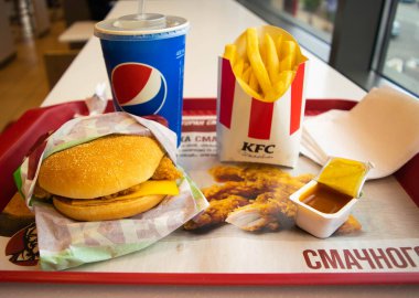 Kiev, Ukrayna - 8 Mart 2020: Popüler bir fast food restoranı olan KFC 'de yiyecek ve içecek. Kentucky Fried Chicken olarak bilinen popüler fast food zinciri. Patates kızartması, Pepsi ve köri soslu burger..
