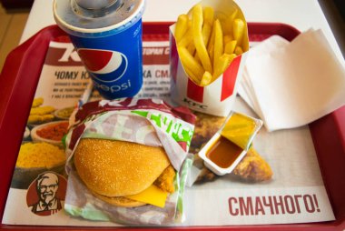 Kiev, Ukrayna - 8 Mart 2020: Popüler bir fast food restoranı olan KFC 'de yiyecek ve içecek. Kentucky Fried Chicken olarak bilinen popüler fast food zinciri. Patates kızartması, Pepsi ve köri soslu burger..