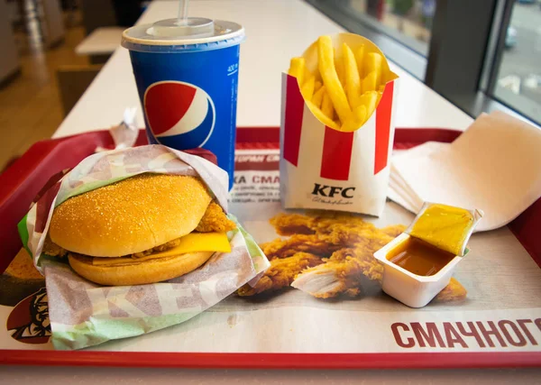 Kiev, Ukrayna - 8 Mart 2020: Popüler bir fast food restoranı olan KFC 'de yiyecek ve içecek. Kentucky Fried Chicken olarak bilinen popüler fast food zinciri. Patates kızartması, Pepsi ve köri soslu burger..