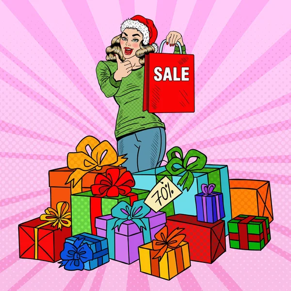 Popart gelukkige vrouw in kerstmuts met boodschappentas en enorme geschenkdozen op Kerstmis verkoop. Vectorillustratie — Stockvector