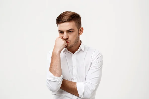 Young successful businessman thinking, posing over white background.