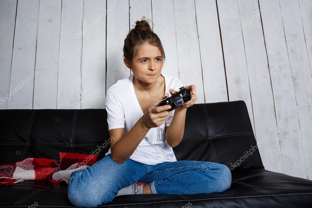 Beautiful girl playing video games, sitting on sofa at Beautiful girl playing video games, sitting on sofa at