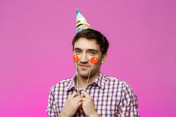 Young handsome man celebrating birthday party over purple background.
