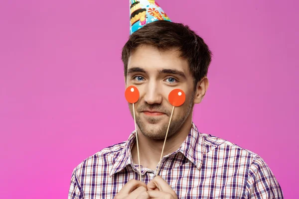 Young handsome man celebrating birthday party over purple background.