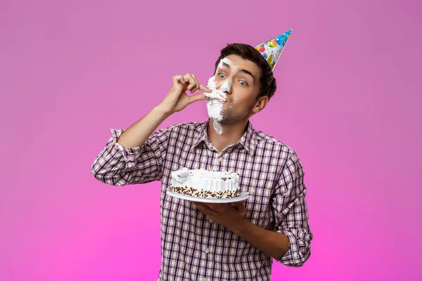 Man with cake on face over purple background. Birthday party.