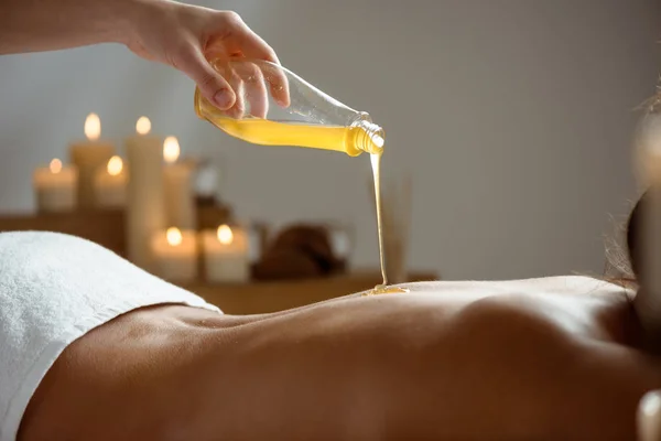 Honey pouring on girls naked back in spa salon.