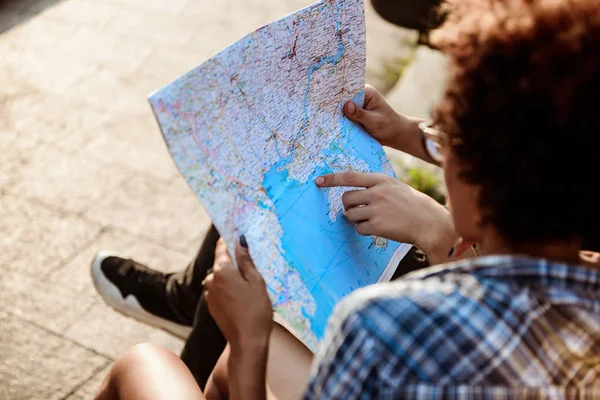 Travelers watching route at map, sitting on bench in park.